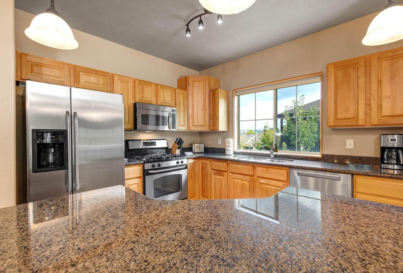 You'll love preparing meals in this bright, fully-equipped kitchen with stainless steel appliances, granite countertops, and natural light streaming through the windows.