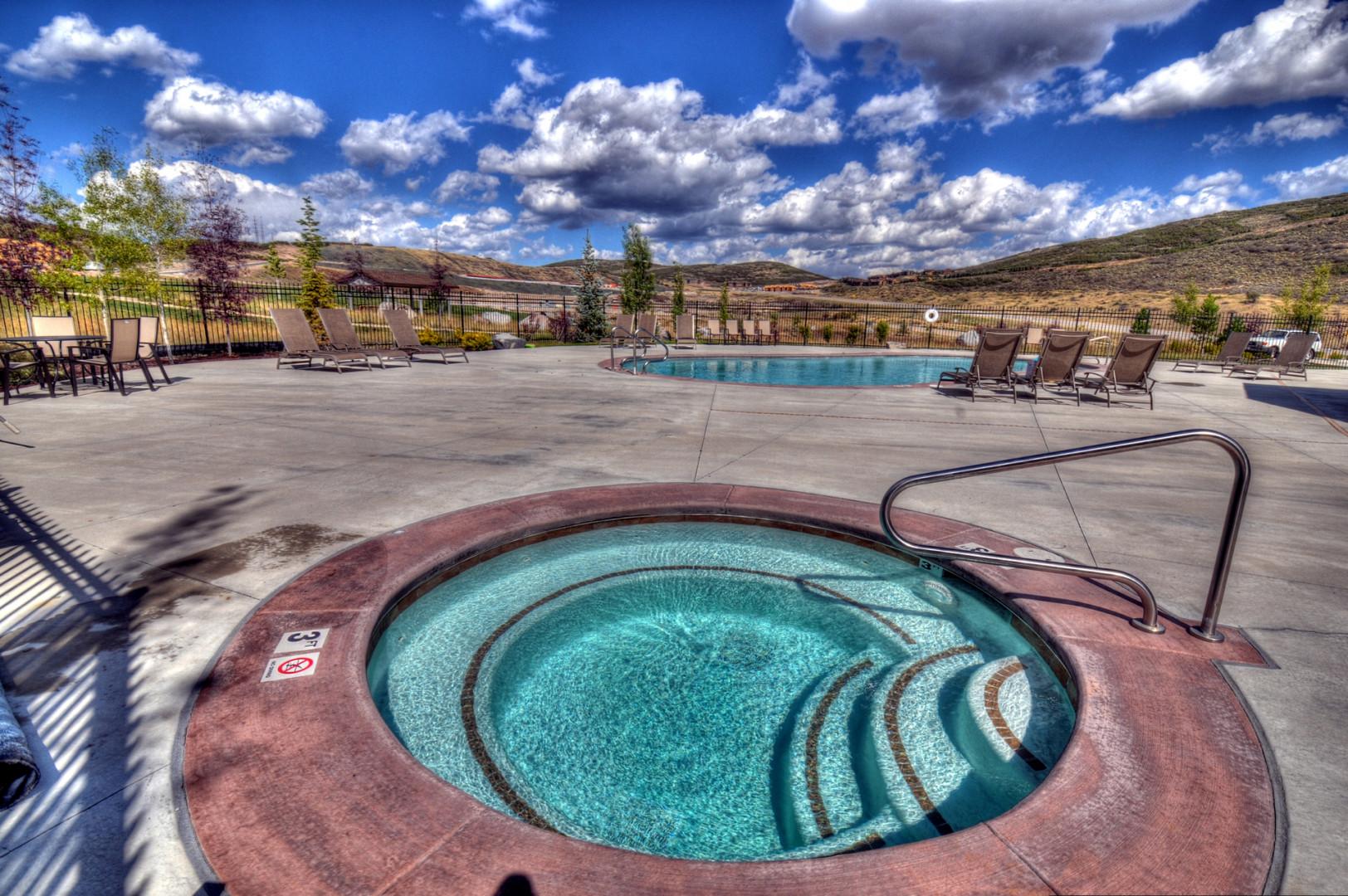 A sparkling hot tub and pool area set against stunning desert hills, offering the perfect spot for relaxation under wide-open skies.