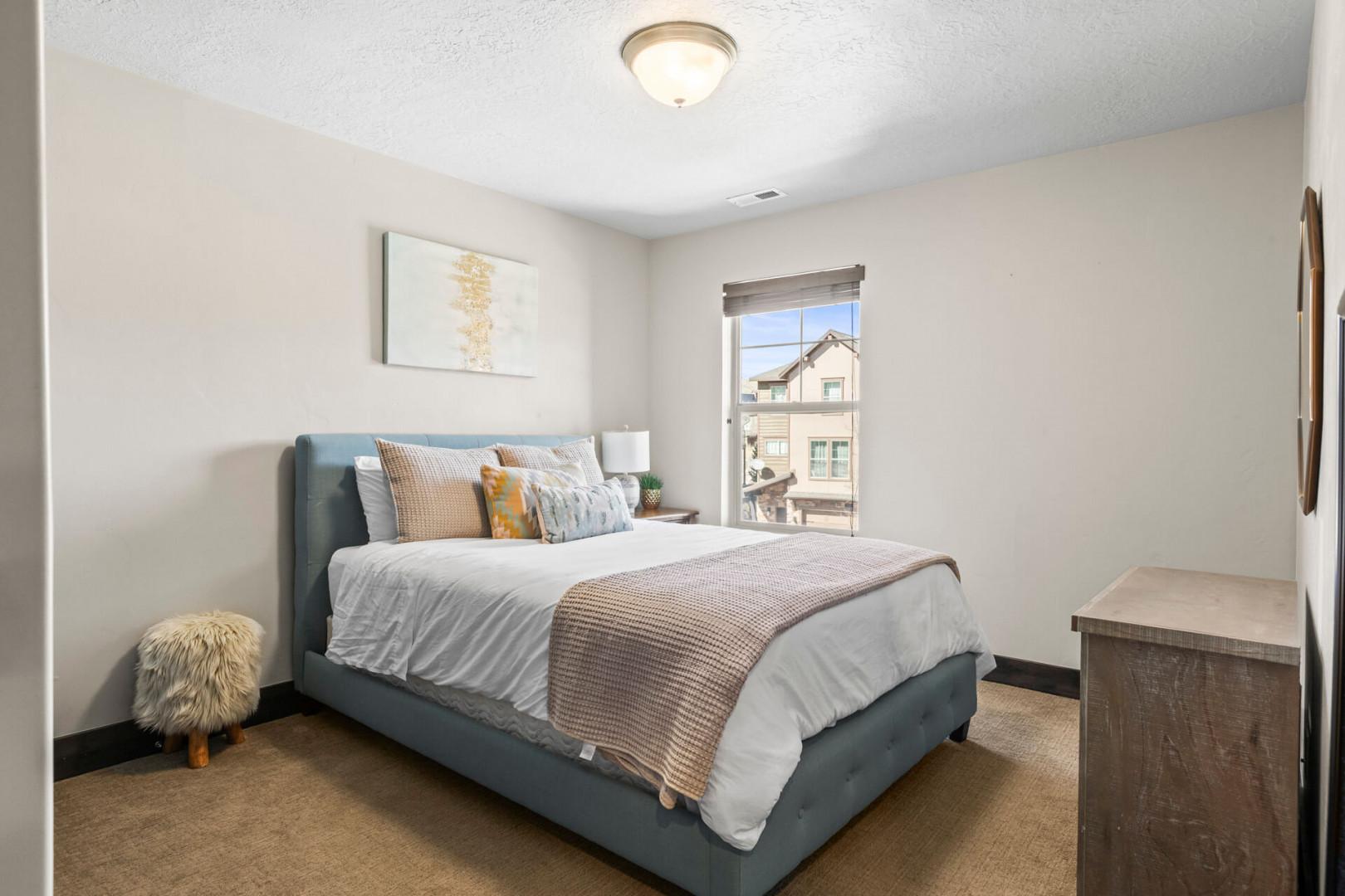 Unwind in this cozy bedroom featuring a plush teal bed with layered linens and modern touches for your perfect retreat.