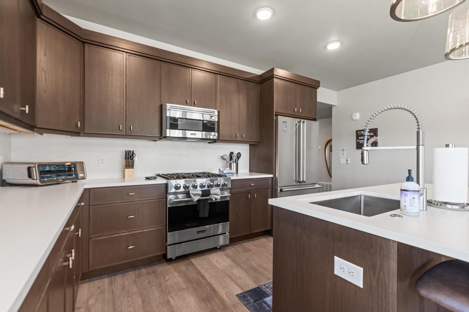 Step into your sleek, fully equipped kitchen with rich wood cabinetry, stainless steel appliances, and a spacious island perfect for meal prep or casual dining.
