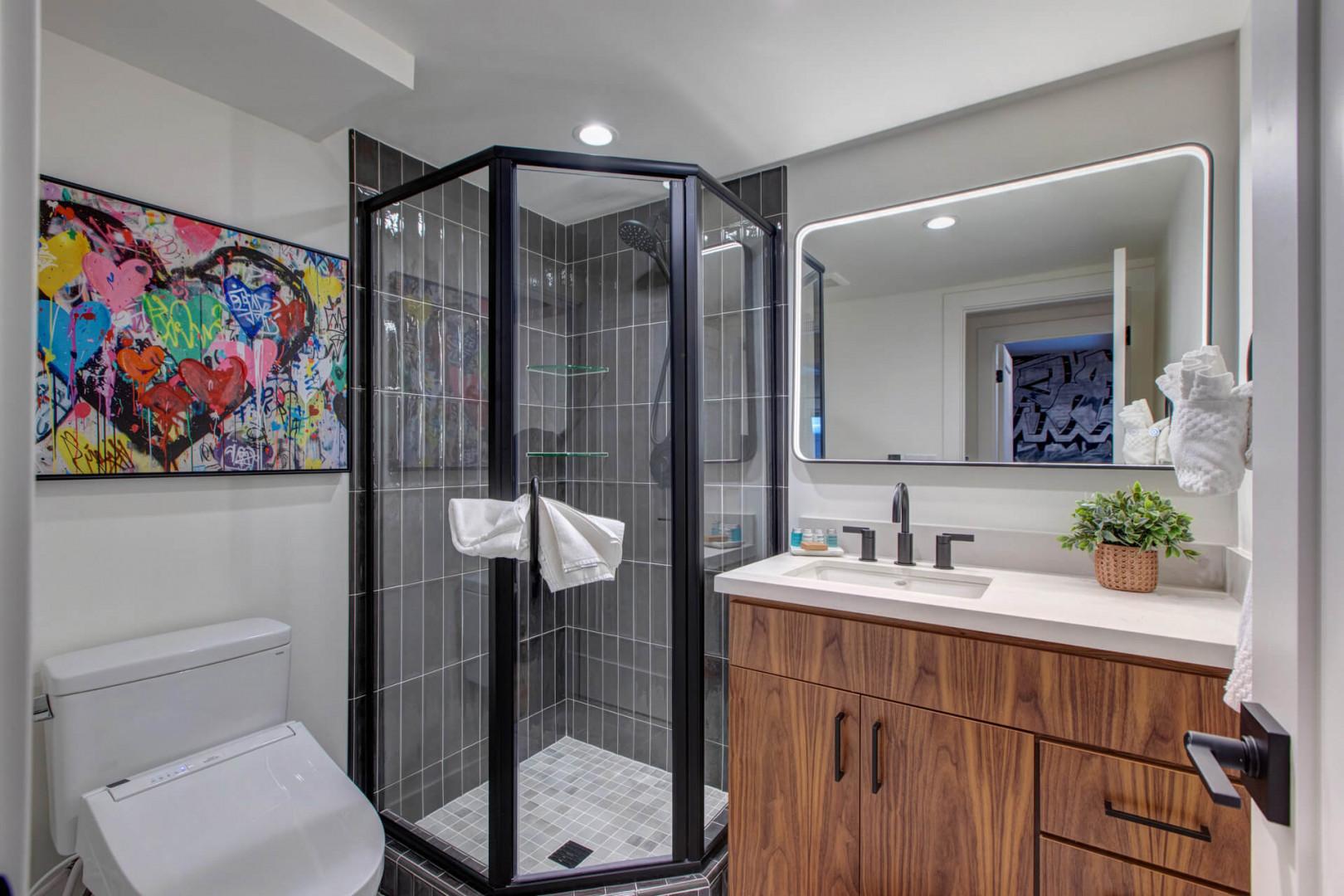 Step into your stylishly designed bathroom featuring a spacious glass shower, modern vanity, and vibrant artwork that adds personality to your private retreat.