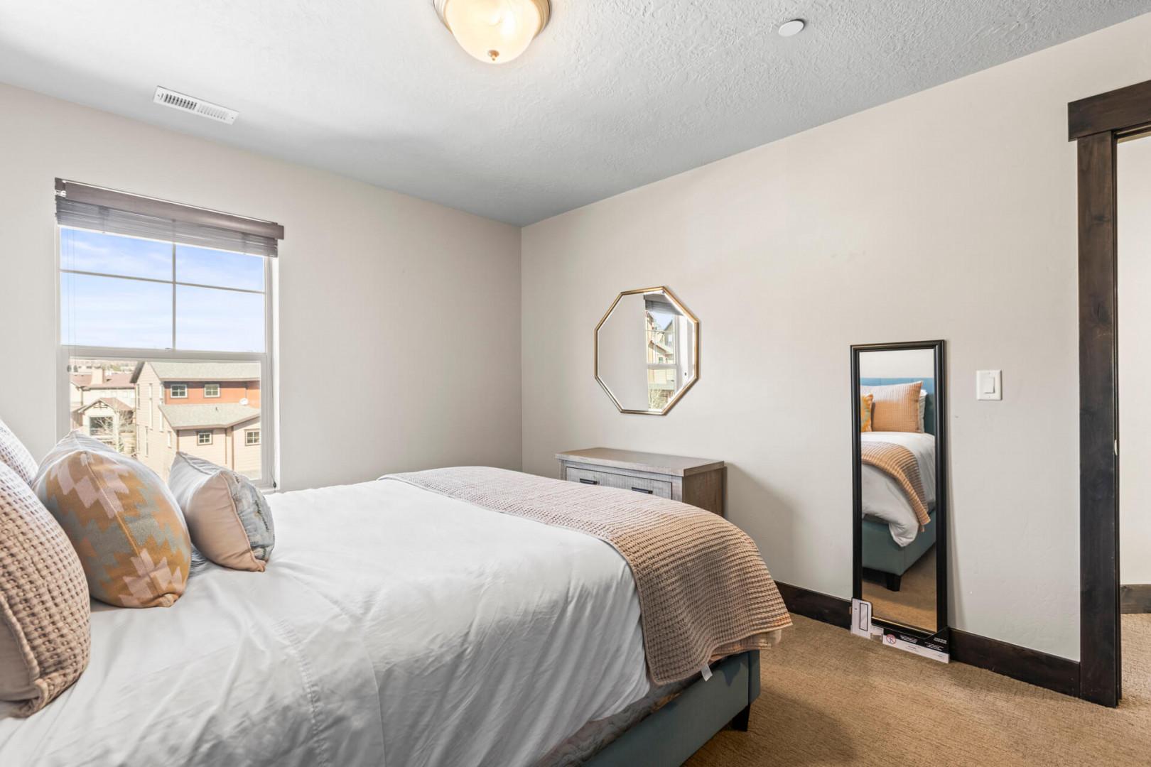 Unwind in your peaceful bedroom with plush bedding and natural light streaming through windows overlooking the neighborhood.