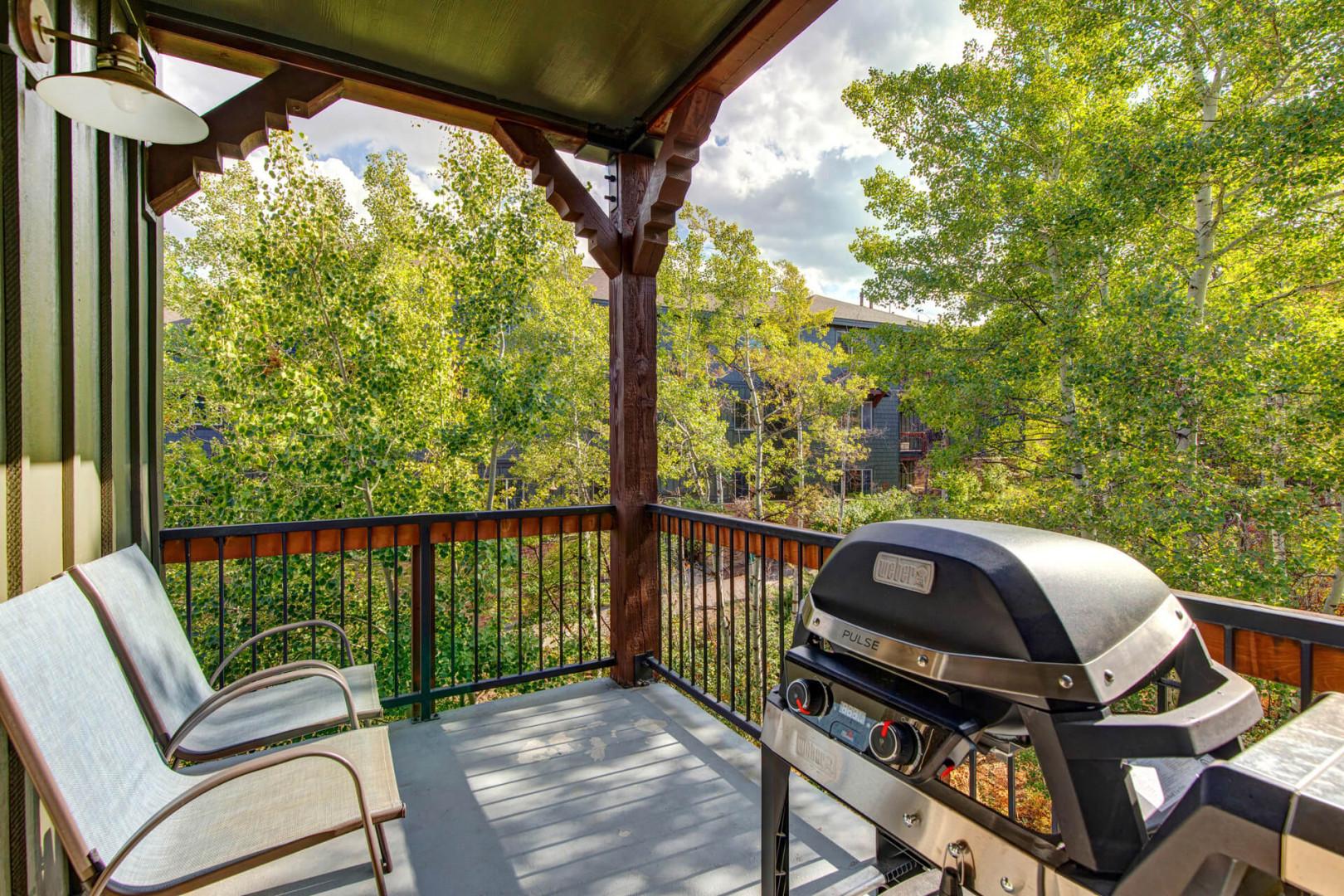 A covered deck surrounded by lush aspen trees and mountain scenery, an ideal setting for grilling and enjoying your morning coffee or evening meal outdoors.