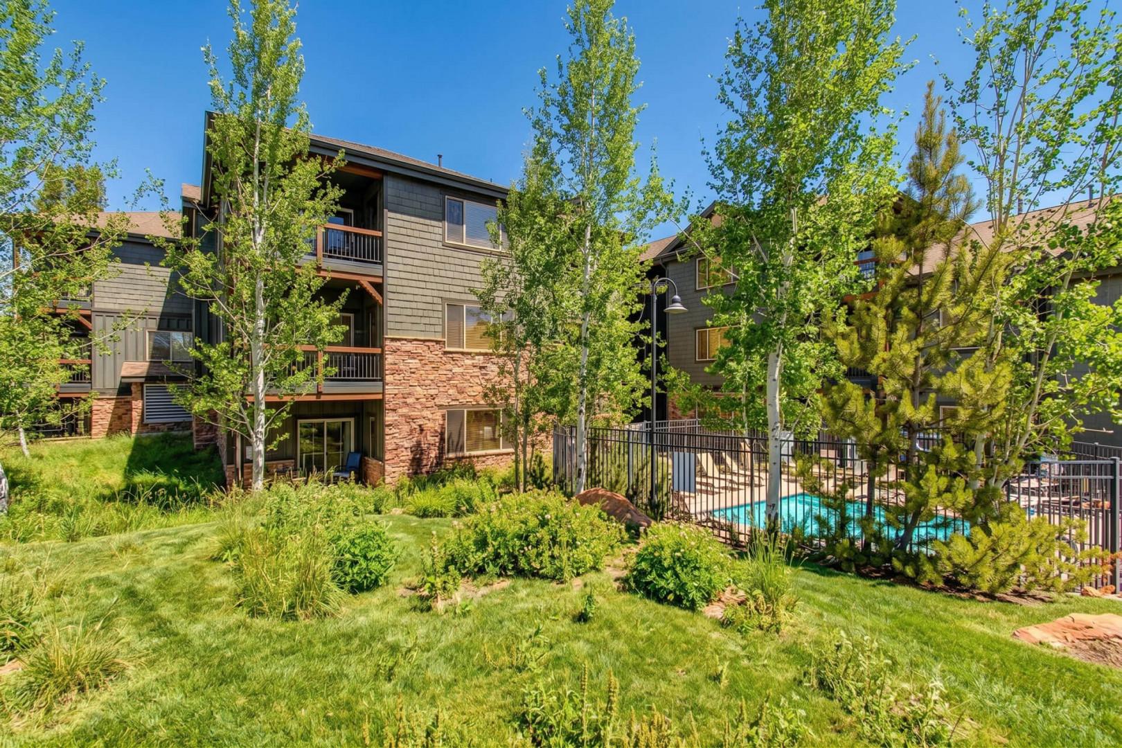 A well-maintained property featuring lush landscaping, mature trees, and a sparkling pool area. The multi-level buildings offer a peaceful retreat in a naturally beautiful setting with ample green space.