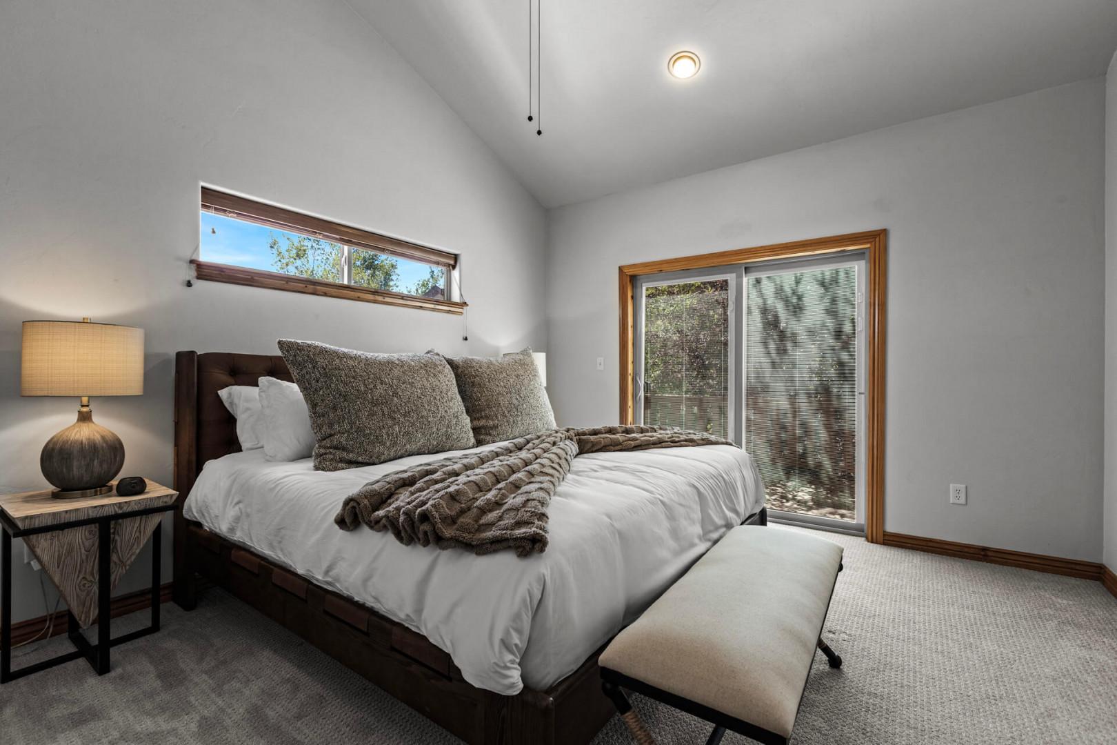 Wake up refreshed in this peaceful bedroom with plush bedding, warm wood accents, and natural light streaming through your private window. The sliding door opens to the outdoors, blending comfort with nature.
