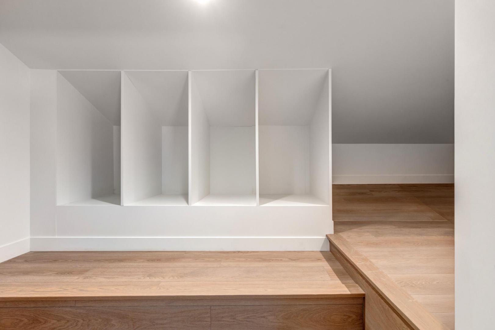 Custom built-in storage keeps your belongings perfectly organized in this sleek, minimalist space with warm wood accents.