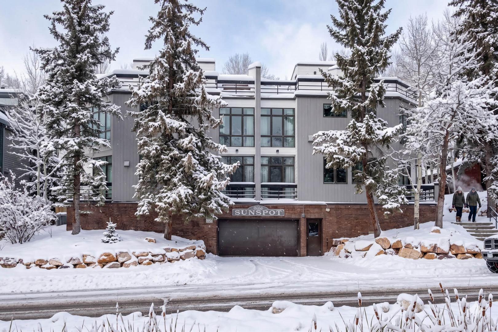 The Sunspot property stands nestled among snow-laden evergreens, offering a serene winter mountain retreat surrounded by pristine natural beauty and peaceful wooded grounds.