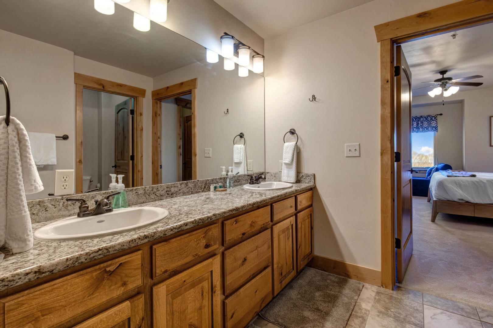 Enjoy your spacious double-vanity bathroom with granite countertops and warm wood cabinetry, perfectly designed for your morning routine.
