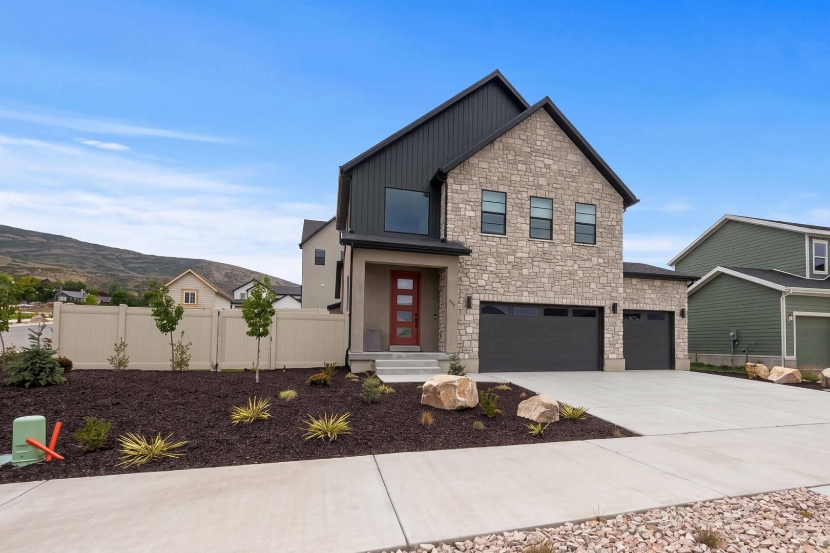 Modern two-story home with contemporary stonework and charming desert landscaping, located in a scenic neighborhood with mountain views.