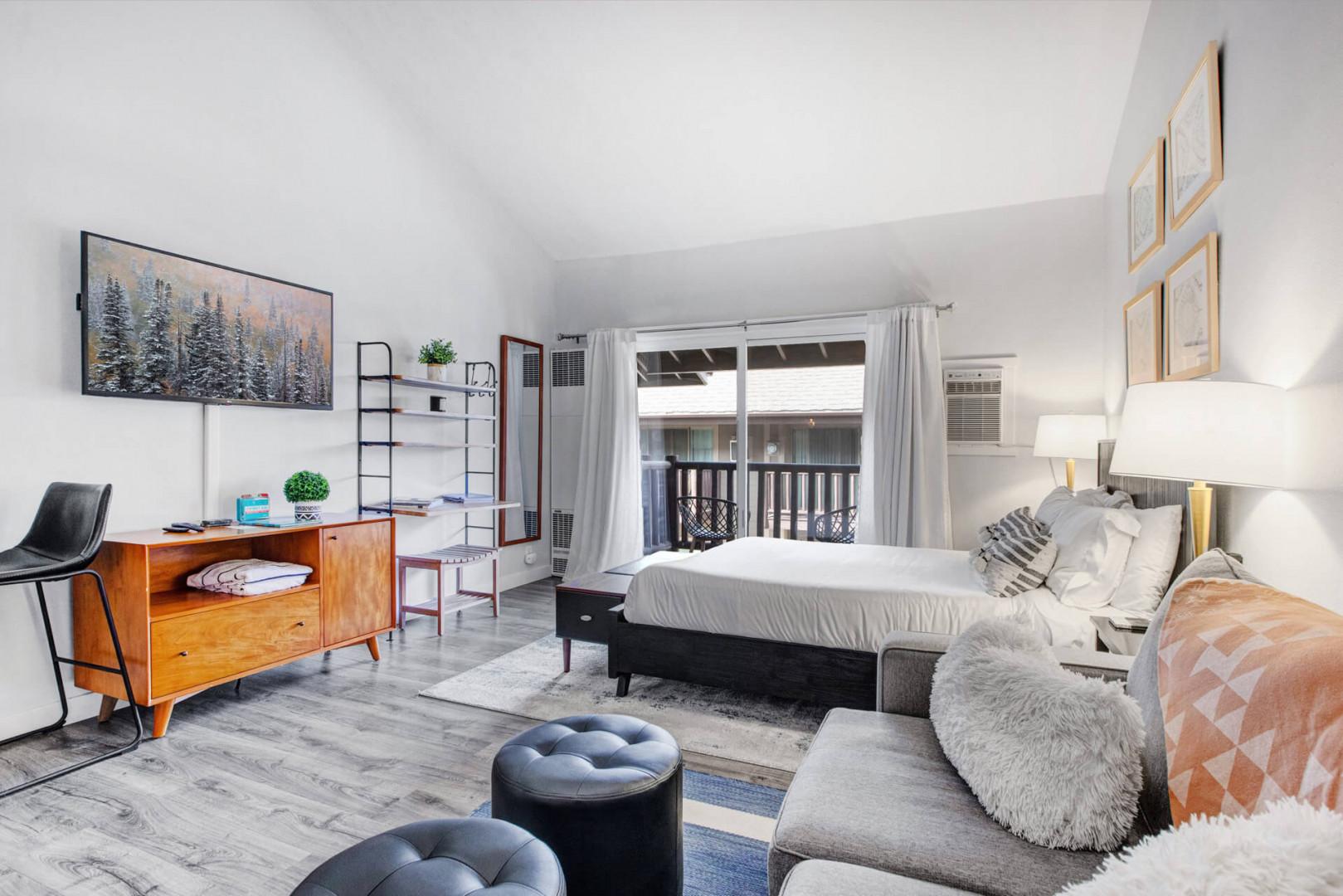 Relax in your stylish studio with modern furnishings, cozy seating, and natural light streaming through your private balcony doors.