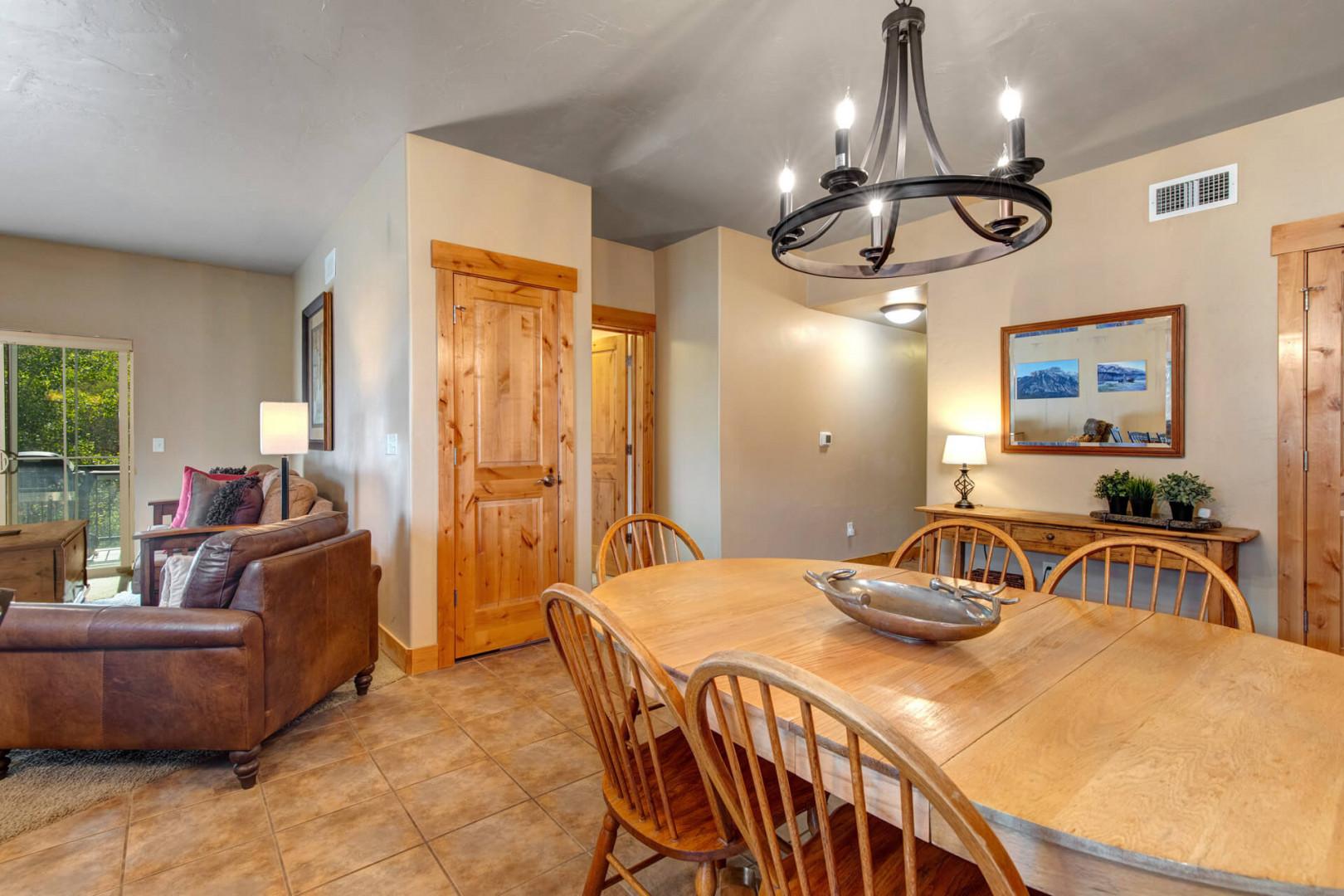 Gather around the spacious dining table under warm chandelier light, perfect for sharing meals and making memories with loved ones. The open layout flows seamlessly into a cozy living area, creating your ideal home base for a mountain getaway.