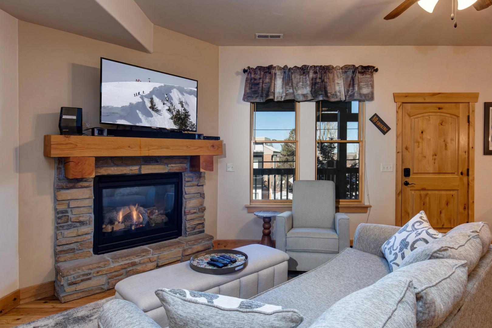 Cozy up by your stone fireplace with mountain views streaming through large windows—perfect for relaxing after outdoor adventures.