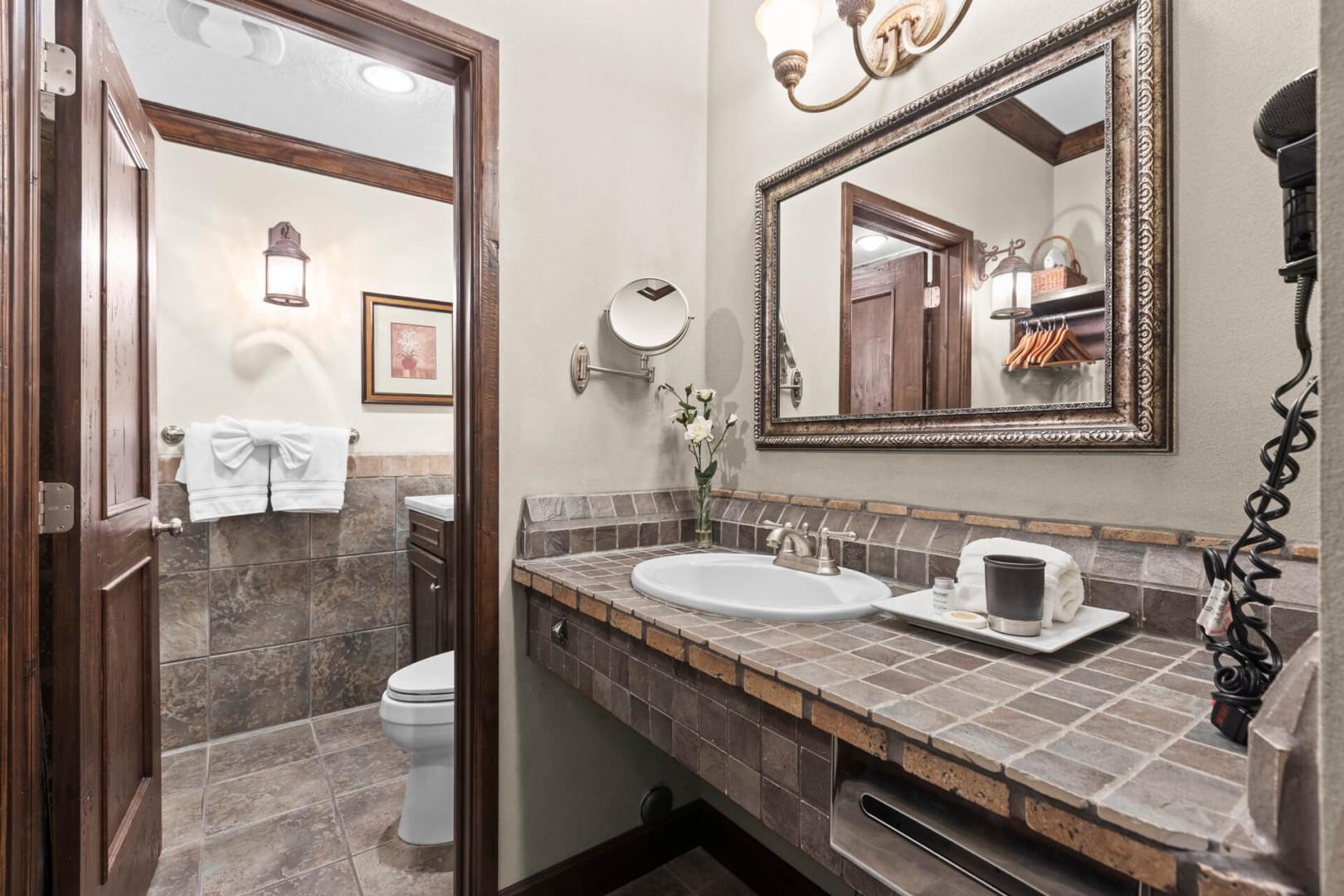 Step into your private bathroom featuring earthy tile finishes, elegant wood framing, and thoughtful touches like fresh flowers and plush towels—your personal retreat awaits.
