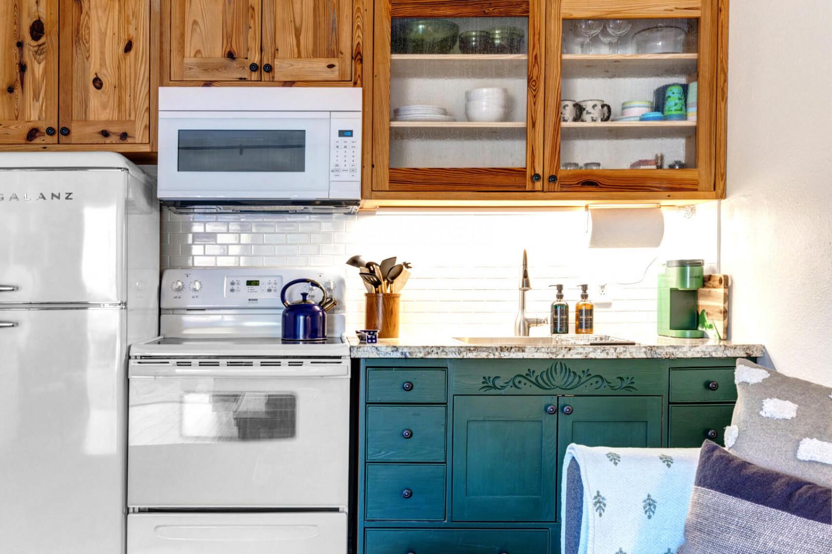 Cozy space with electric range, wood cabinets, and modern appliances.