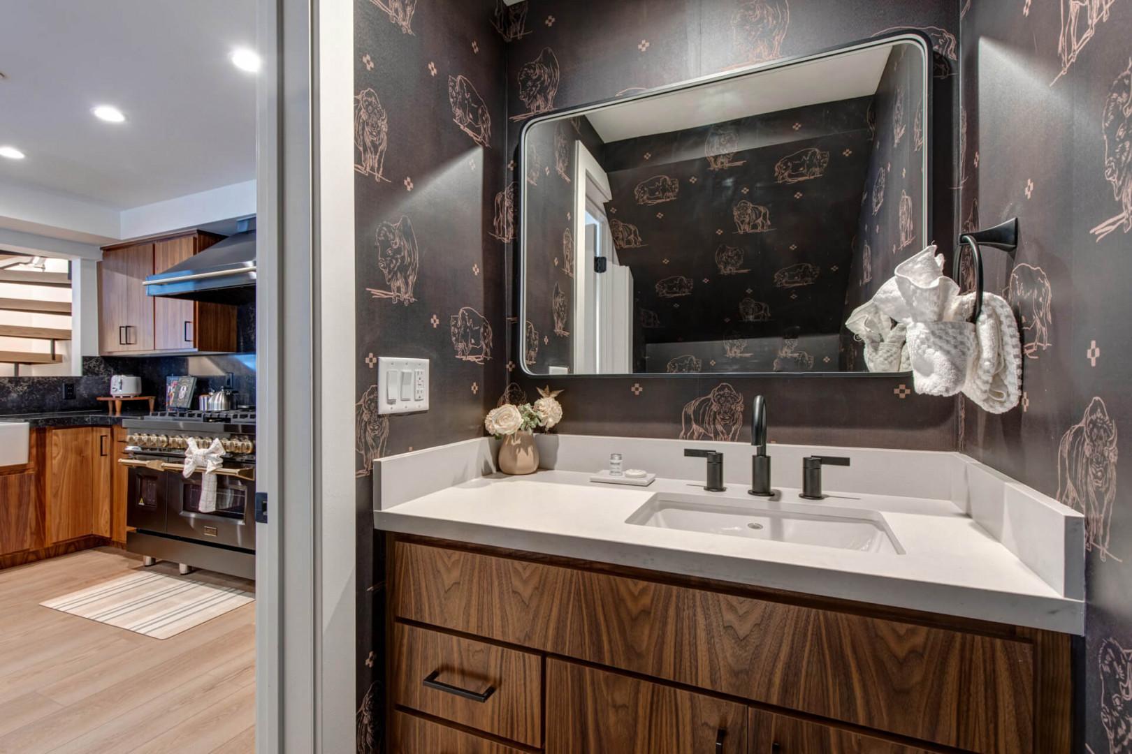 Upper Main 301: Freshen up in this stylish half bathroom located adjacent to the kitchen, featuring bold botanical wallpaper and sleek modern fixtures. Perfect for a quick touch-up.