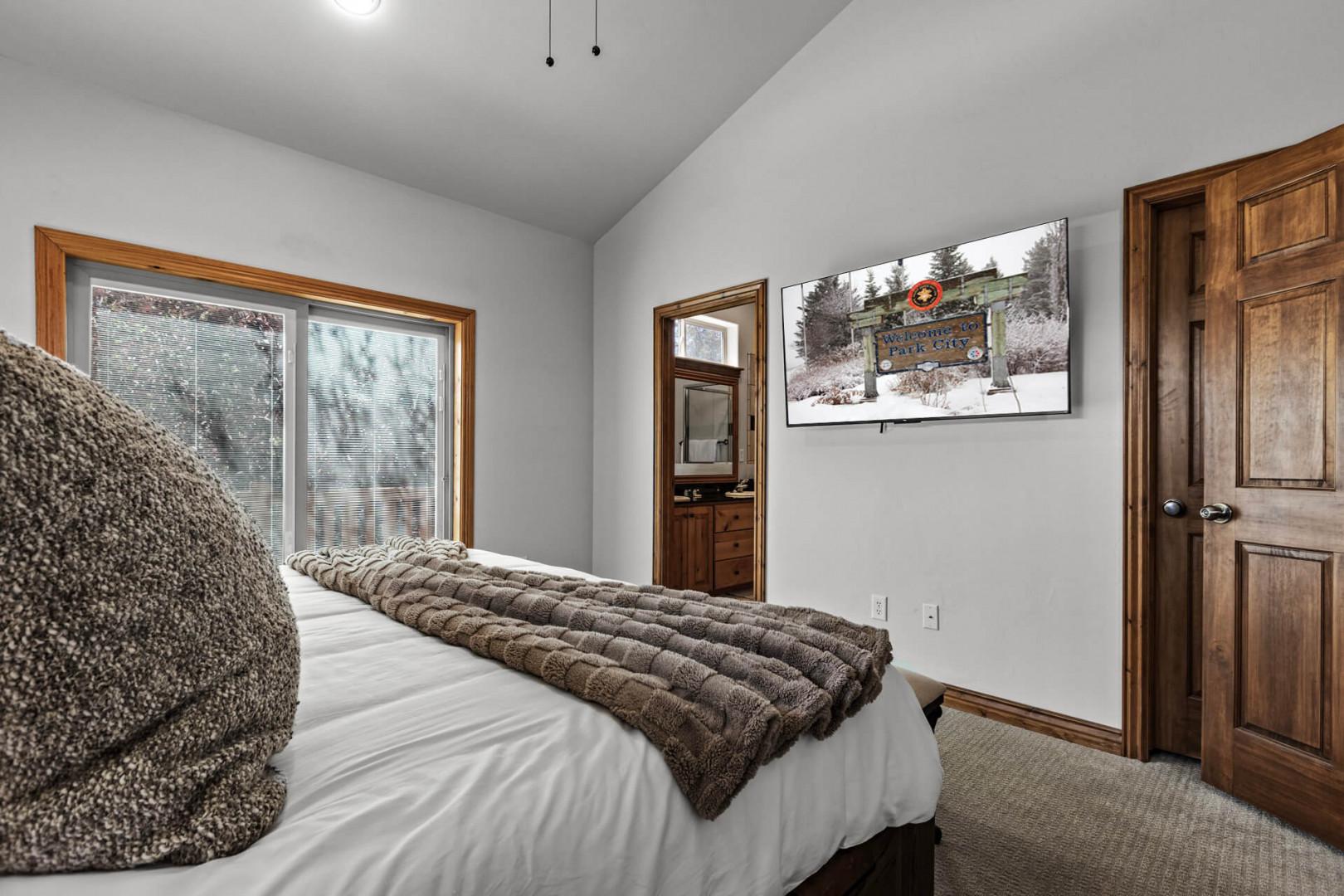 Sink into plush bedding and peaceful mountain-inspired decor as natural light fills your restful retreat. With vaulted ceilings and warm wood accents, this cozy bedroom offers the perfect escape after a day of adventure.