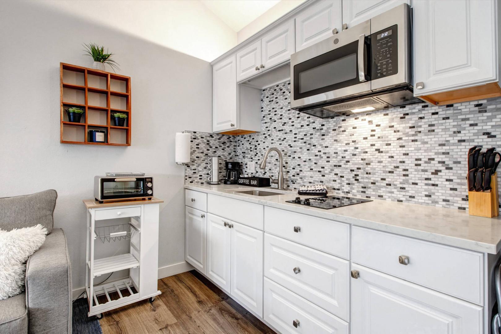 Your bright, modern kitchen features white cabinets, stylish mosaic backsplash, and everything you need to prepare meals during your stay.