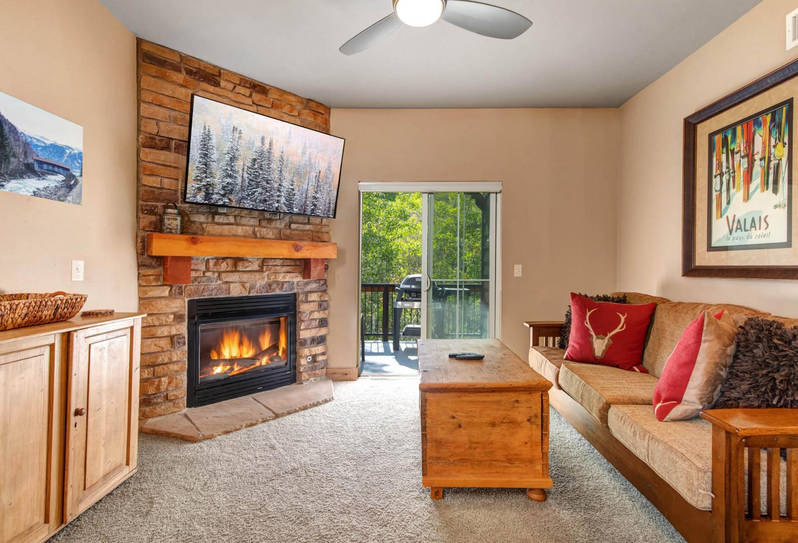 Cozy up in your inviting living room with a warm fireplace, mountain artwork, and access to your private balcony overlooking nature.