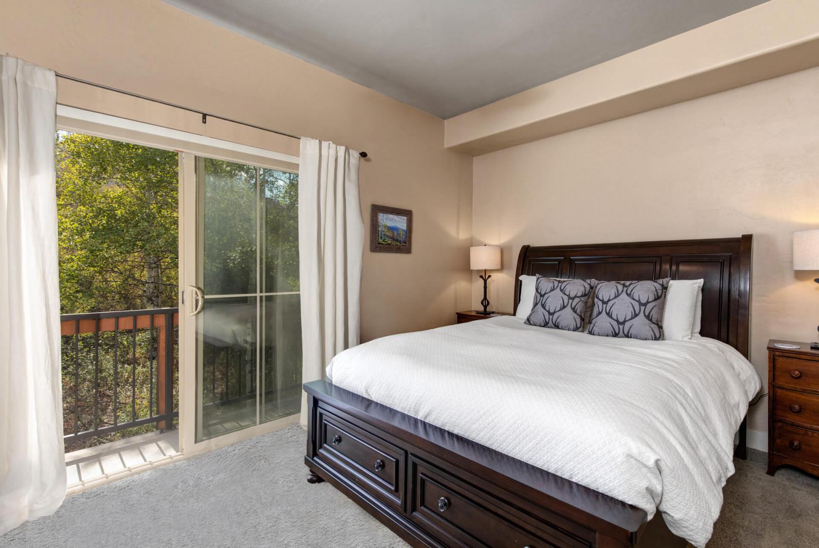 Sink into your crisp white bedding and drift off as natural light filters through the balcony doors, framing peaceful treetop views that promise restful mornings.