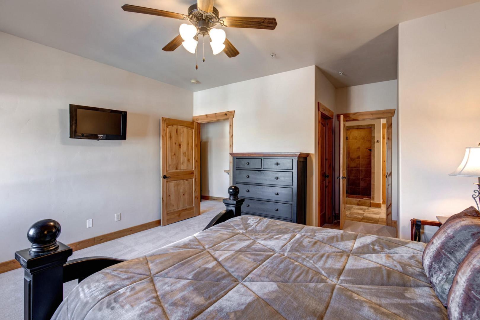 Unwind in your spacious bedroom with cozy furnishings, ceiling fan for comfort, and TV for relaxation after mountain adventures.