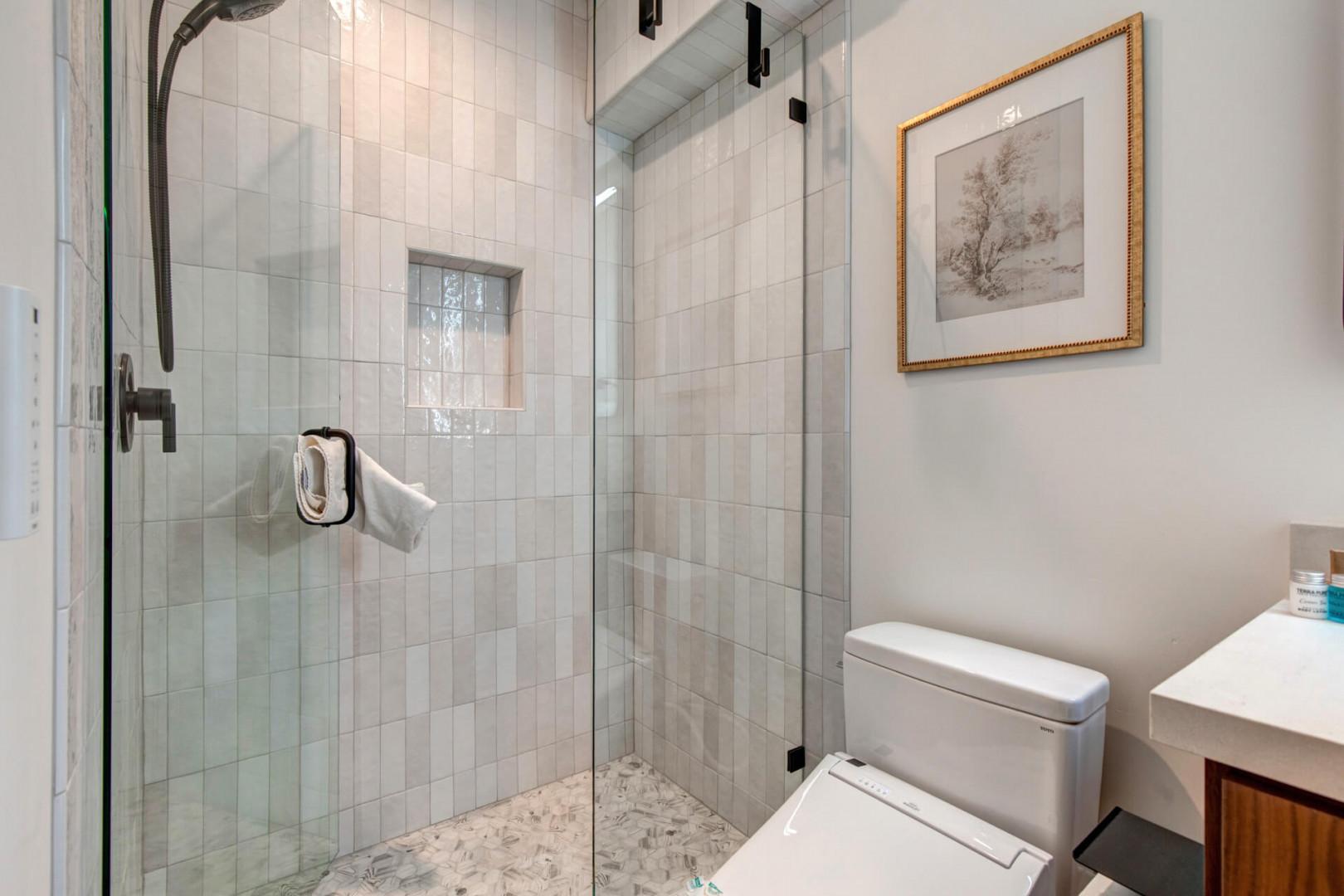 Upper Main 301: Your private bathroom features a spacious glass-enclosed shower with elegant tiled walls and modern fixtures for a refreshing start to your day.
