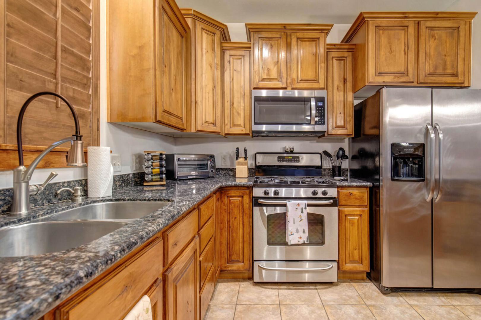 Cook with ease in your fully equipped kitchen, featuring rich wood cabinetry, granite countertops, and stainless steel appliances.