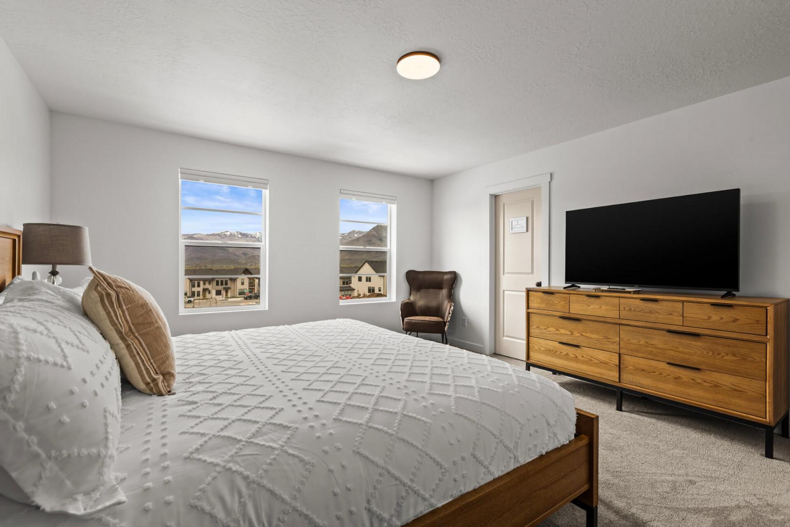 Unwind in your serene bedroom with mountain views, cozy textured bedding, and modern amenities for peaceful nights.