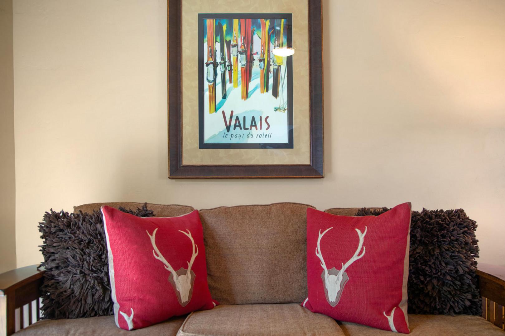 Sink into a cozy sofa adorned with alpine-inspired pillows, beneath charming ski resort artwork that sets the tone for your mountain escape.