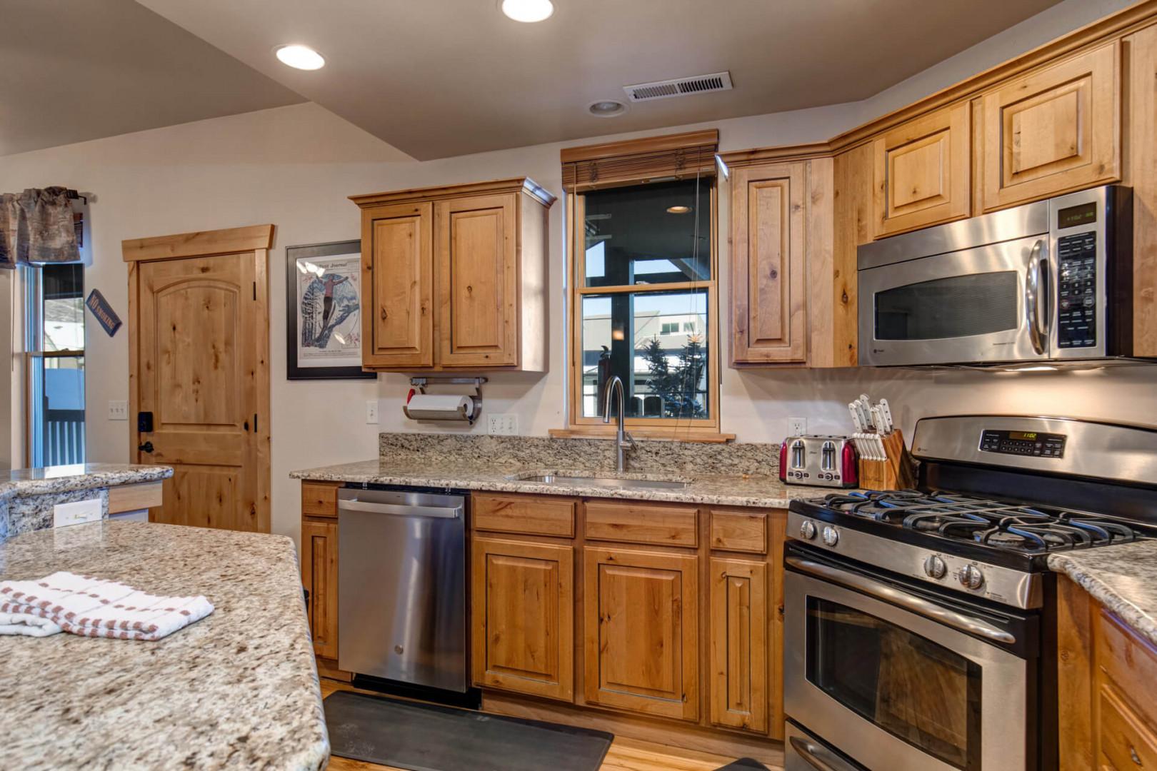Your fully equipped kitchen features granite countertops, stainless steel appliances, and warm wood cabinetry - perfect for preparing memorable meals during your stay.