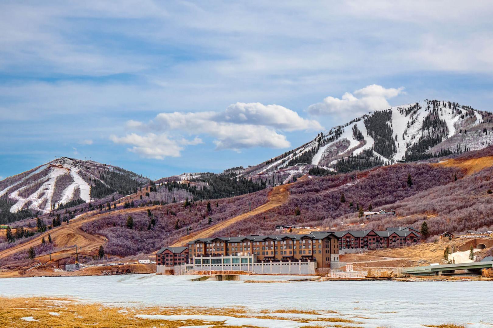 Mountain resort property nestled in a stunning alpine valley with ski slopes and seasonal terrain surrounding the building.