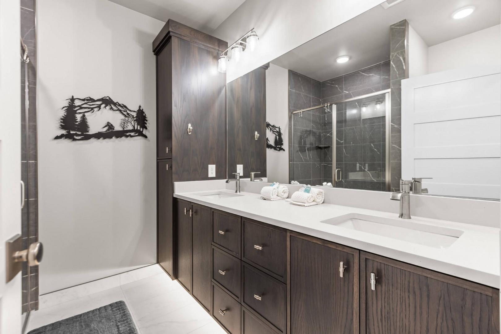 Your private spa-like bathroom features a sleek double vanity, modern walk-in shower, and rich wood cabinetry—perfect for unwinding after a day of adventure.
