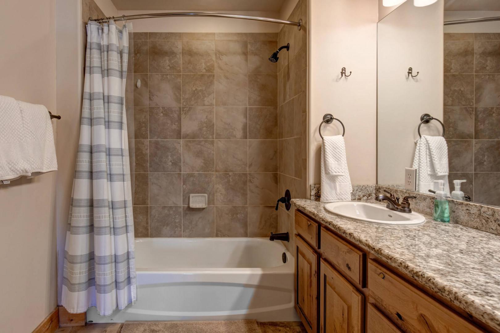 Your private bathroom features elegant granite countertops, warm wood cabinetry, and a relaxing tub-shower combo for unwinding after your adventures.