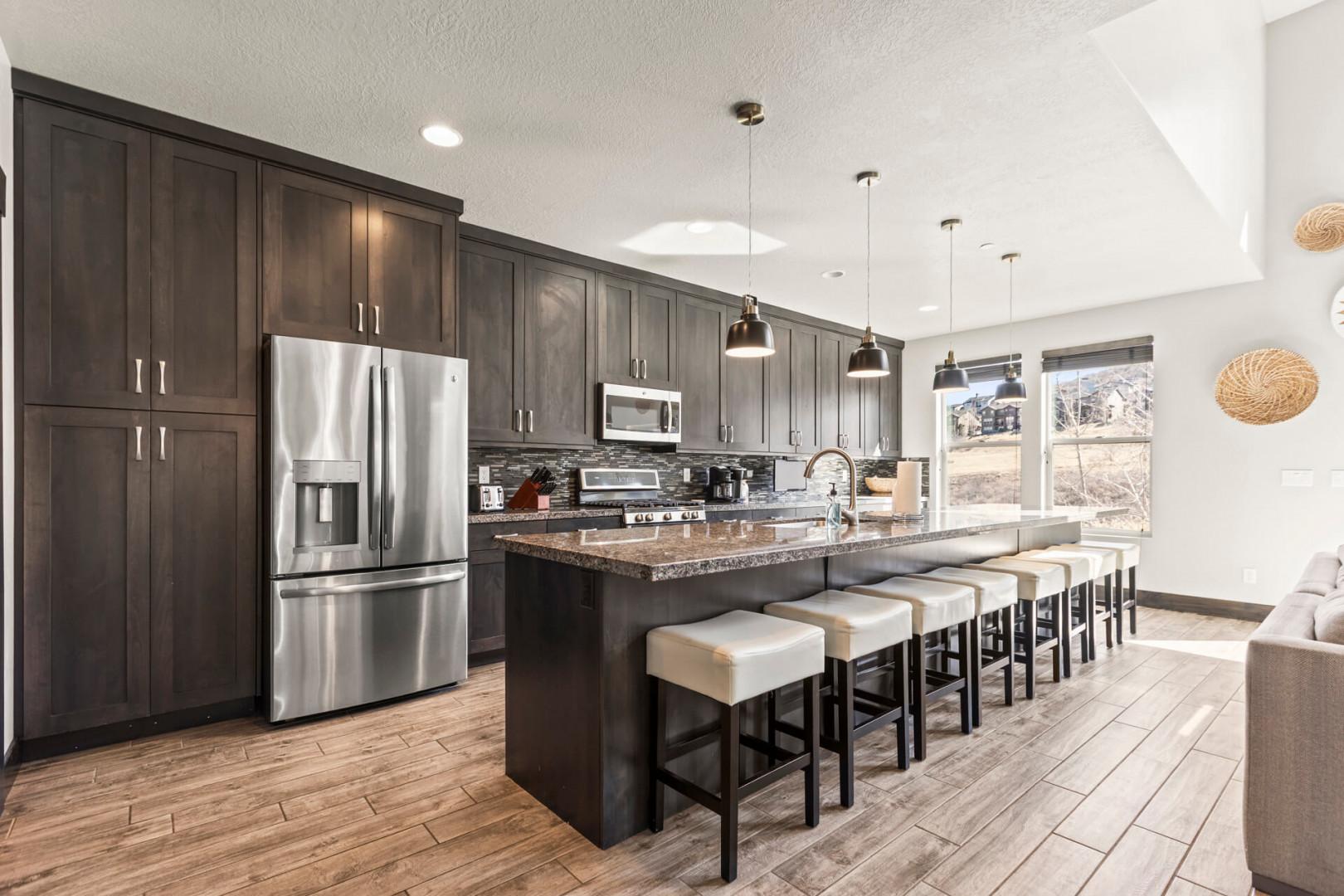 Gather around the spacious island with your group in this modern kitchen, featuring granite counters, stainless steel appliances, and warm wood-toned floors bathed in natural light.