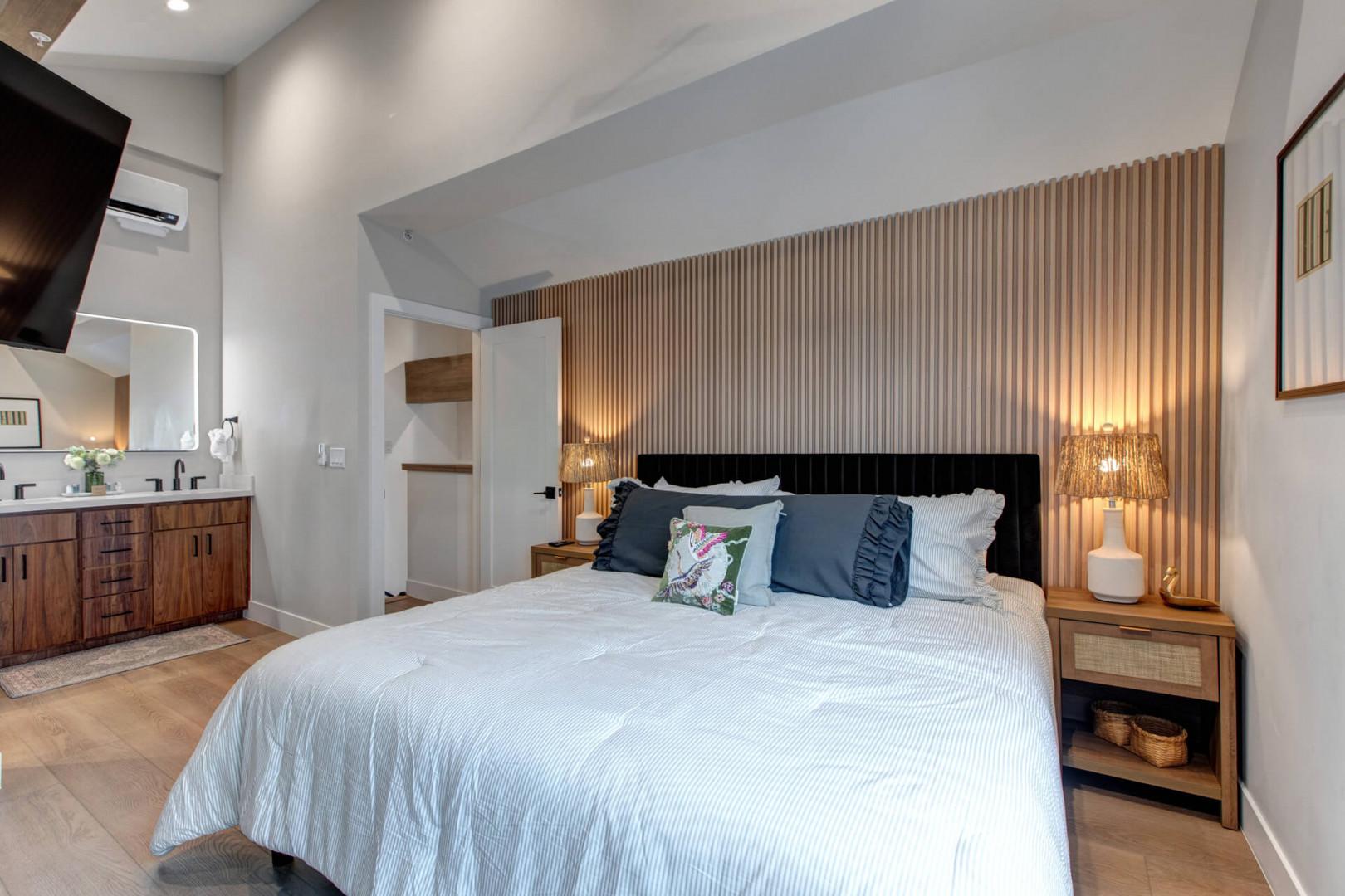 Rest peacefully in your modern bedroom featuring a striking wood accent wall, crisp linens, and warm bedside lighting for ultimate comfort.