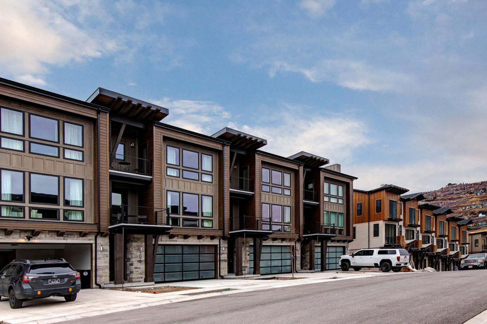Modern mountain townhomes with stone and wood architecture nestled in a scenic hillside neighborhood.