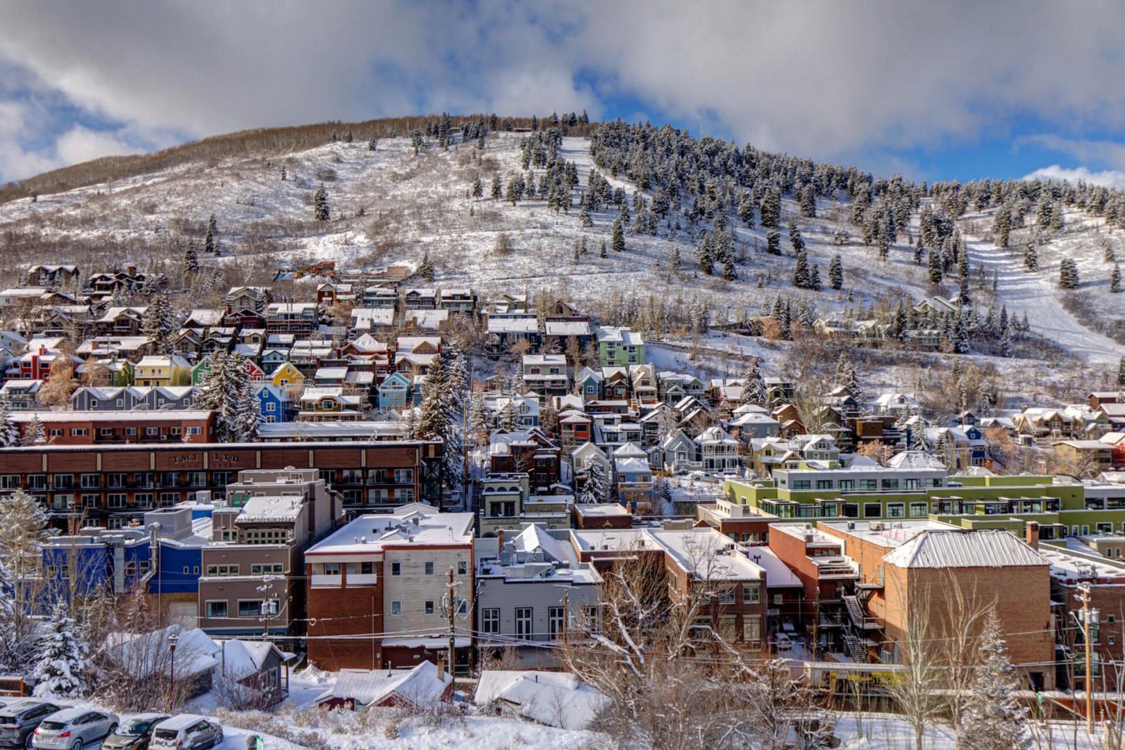 Charming mountain town nestled beneath snow-covered ski slopes, featuring colorful buildings and winter scenery.