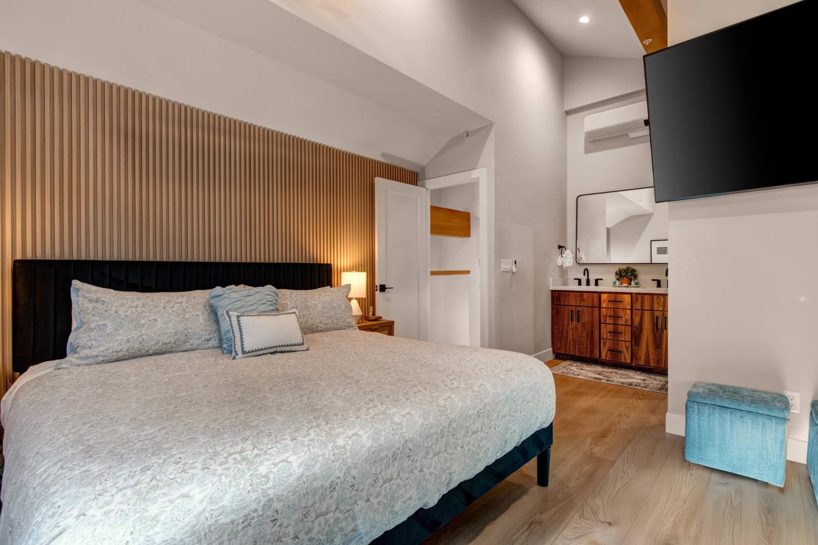 Upper Main 301: Unwind in your tranquil bedroom sanctuary, where warm wood slats create intimate ambiance and luxury meets comfort in every detail.