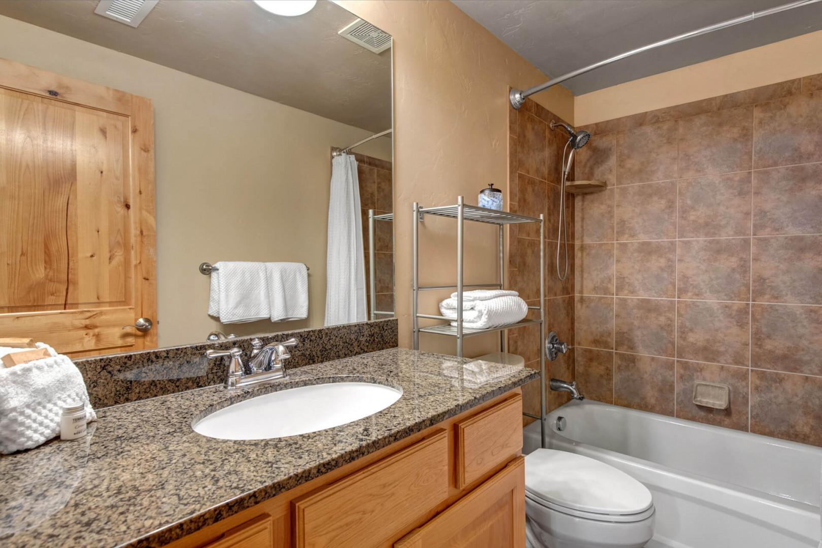 Step into your private bathroom featuring a tub-shower combo, granite counters, and fresh towels—everything you need to refresh after a day of exploring.