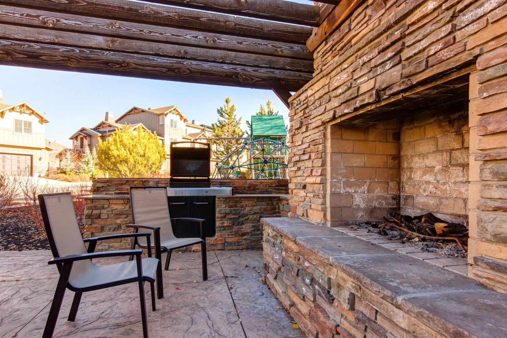 Unwind on your private patio beside a crackling stone fireplace, with a built-in grill ready for alfresco meals under rustic timber beams and open skies.