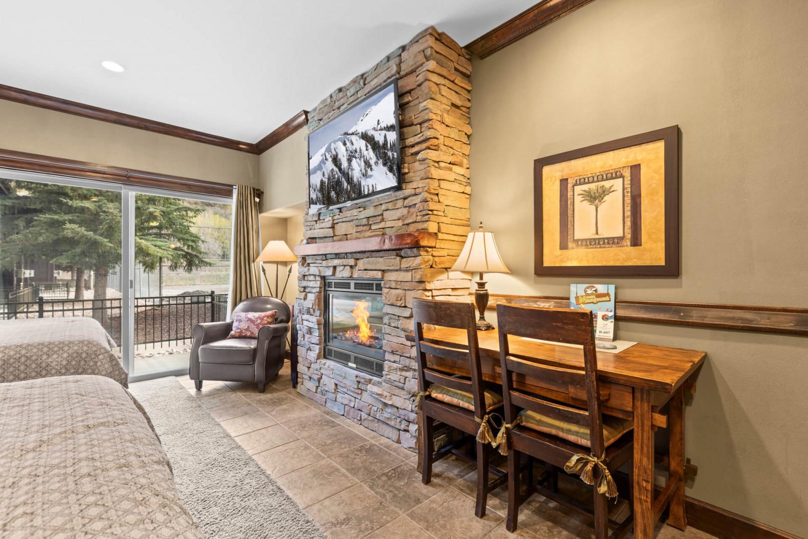 Unwind in your cozy living space with a crackling stone fireplace, large TV for movie nights, and a rustic dining nook. The balcony invites you to enjoy mountain views and fresh air.