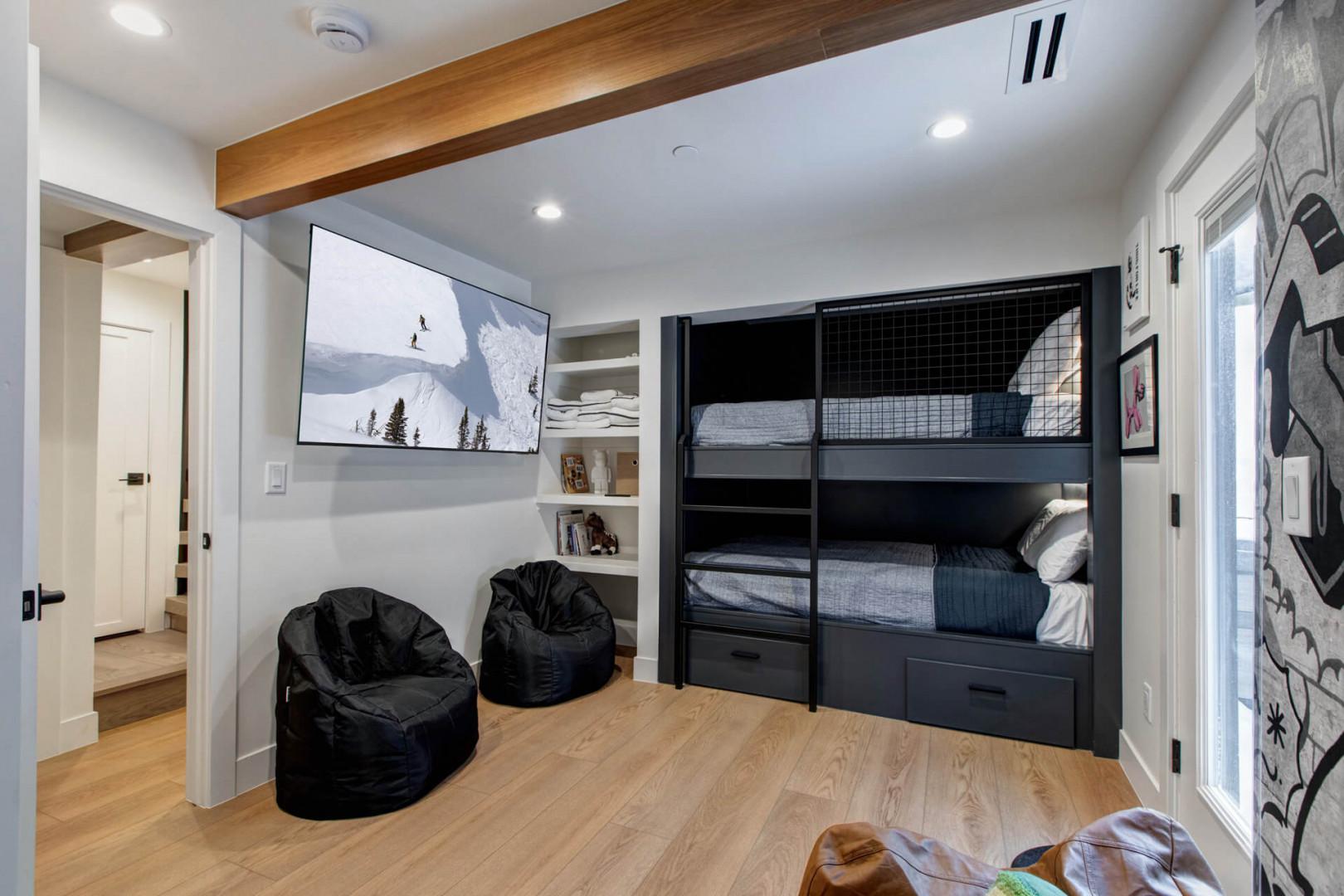 Cozy up in your modern bunk room with built-in beds, bean bag seating, and entertainment center—perfect for kids or groups.