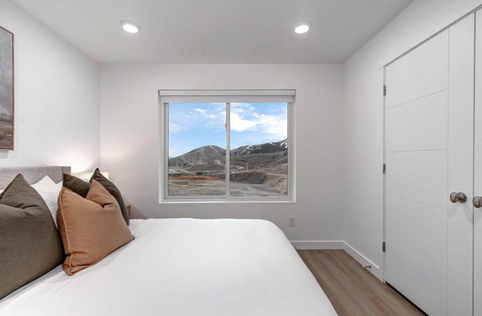 Wake up to stunning mountain views from your comfortable bed in this bright, modern bedroom with ample storage space.