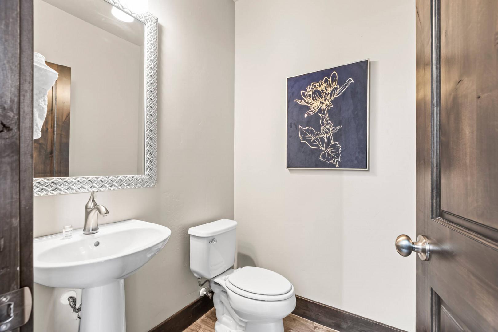 Step into a cozy, well-appointed powder room with a modern vessel sink, elegant framed mirror, and charming décor—designed for your comfort and convenience.