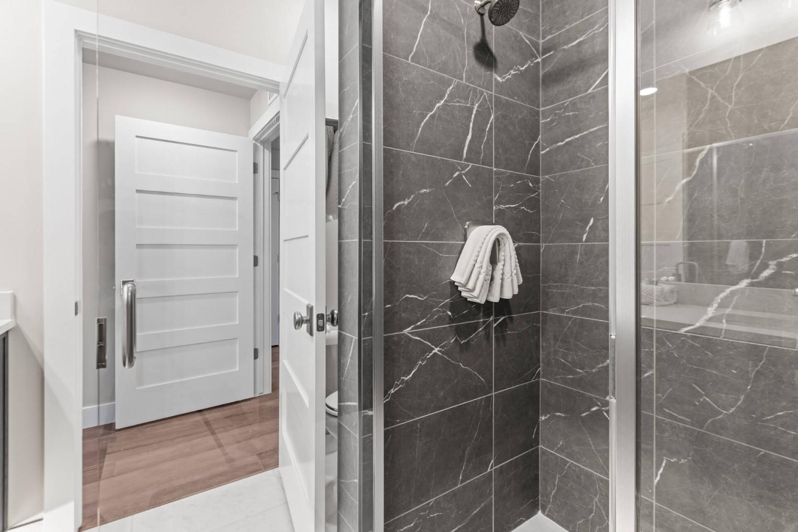 Step into your private sanctuary with a stunning walk-in shower wrapped in elegant marble tile and a fresh towel waiting just for you.