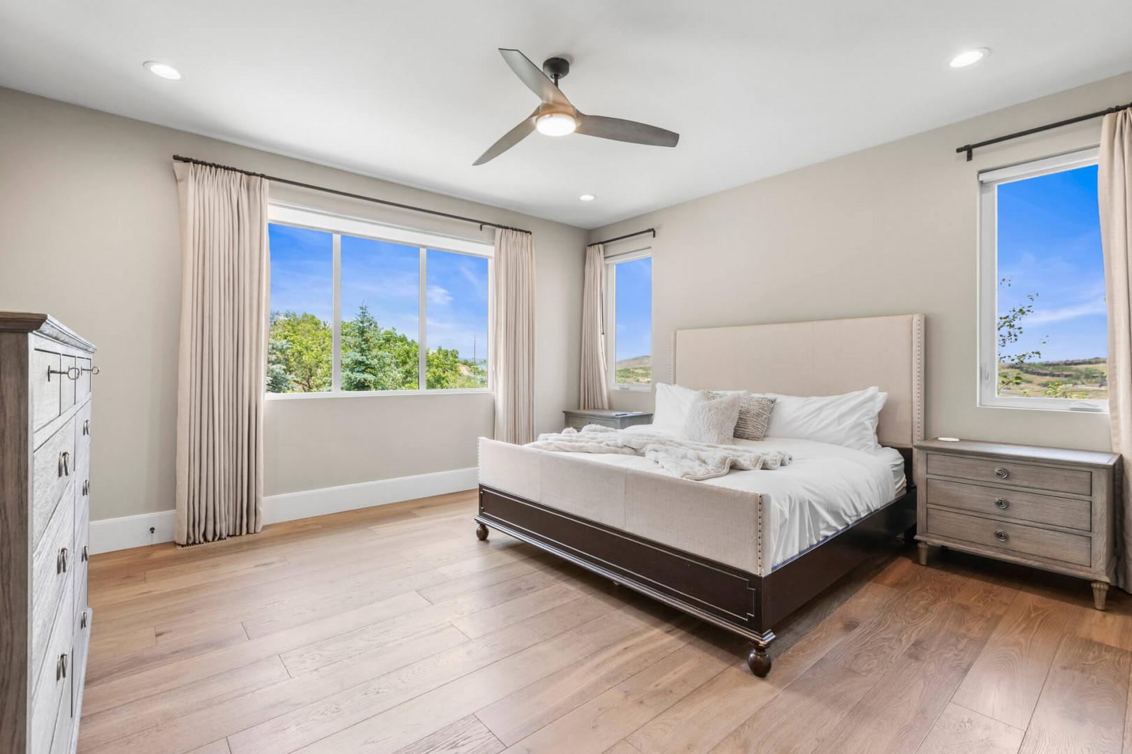Sink into the plush king-sized bed and let natural light fill your serene retreat, where modern comfort meets peaceful hillside views through oversized windows.