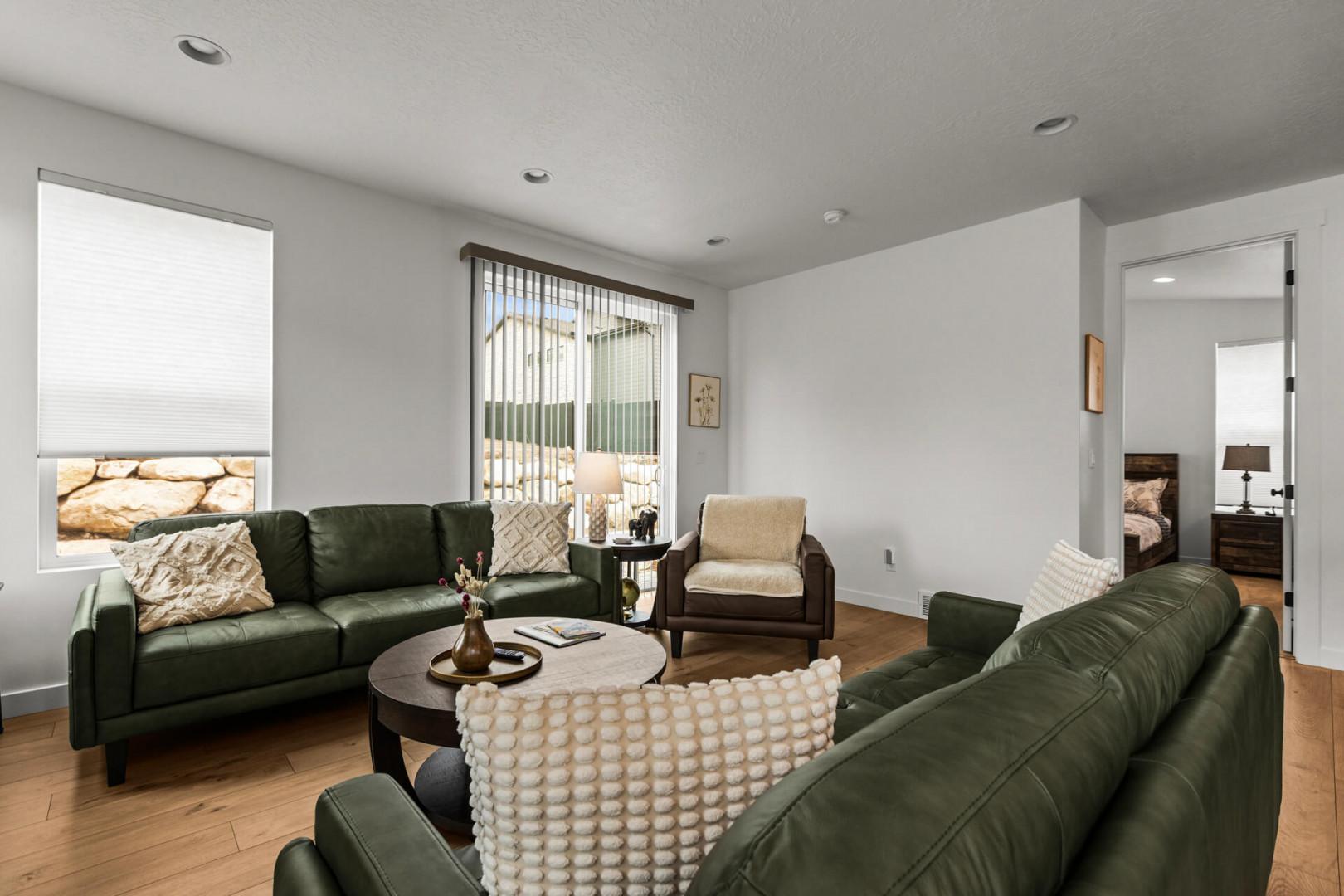 Sink into plush green leather sofas in your bright, modern living room with natural light streaming through large windows.