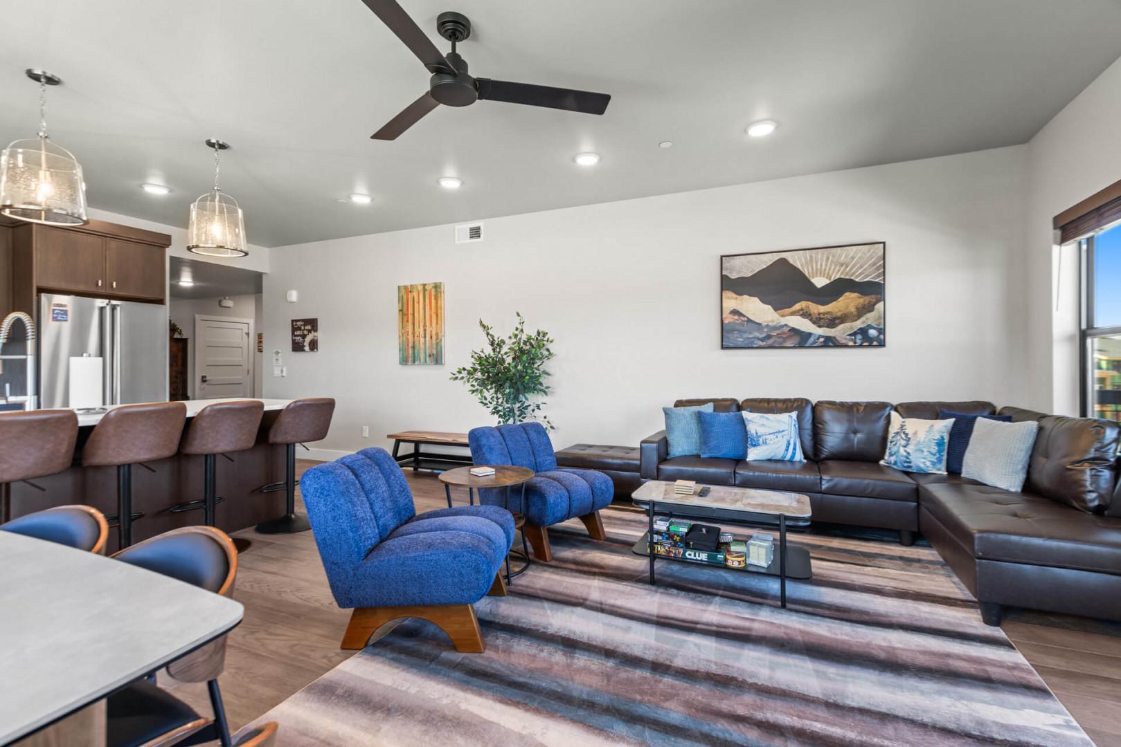 Settle into your open living area where a sleek leather sectional and vibrant blue chairs invite relaxation. The modern kitchen beckons just steps away, ready for your morning coffee or evening meals.