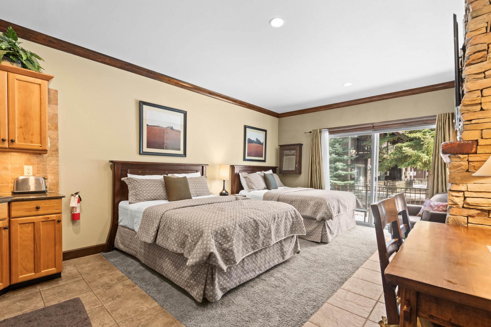 Unwind in your spacious retreat featuring two plush beds, a cozy kitchenette, and sliding glass doors opening to your private outdoor space with mountain views.