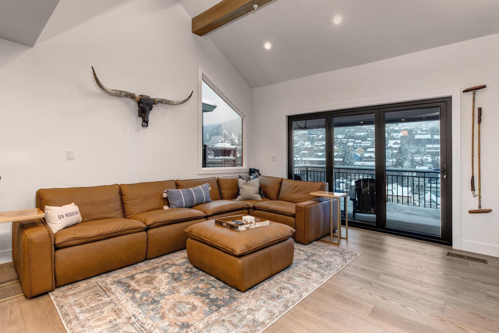 Upper Main 301: Sink into luxurious leather seating while enjoying stunning mountain views through floor-to-ceiling windows in your cozy living room retreat.