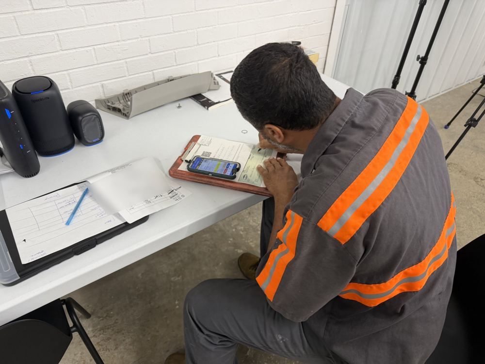 Tow truck driver writing the shop a check at a table in the shop